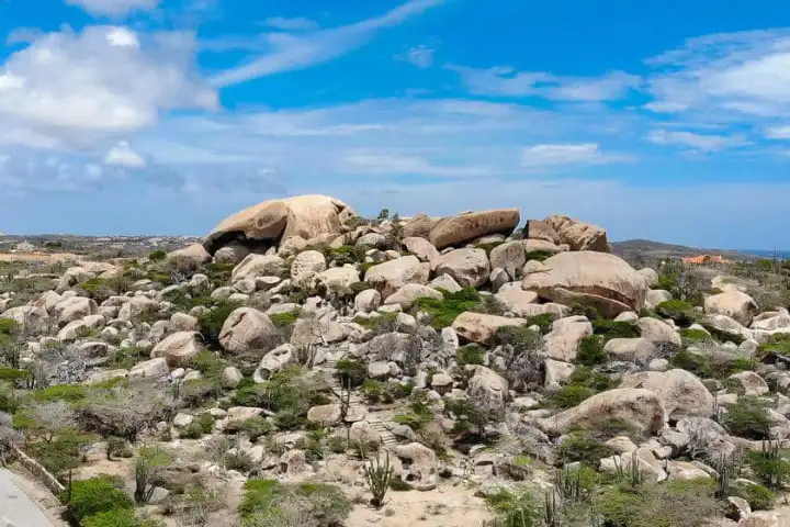 Rock formation with scattered greenery under a blue sky.