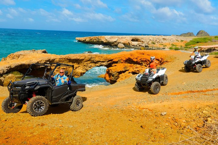 a group of parked motorcycles sitting on top of a sandy beach
